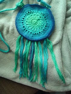 A crochet round bag with tassels laid on a bed. Circle Purse Pattern, Crochet Crossbody Bag