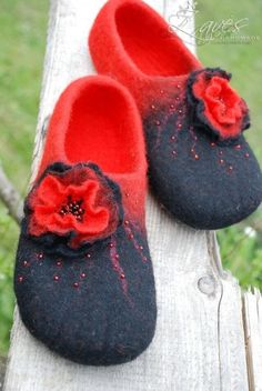 two pairs of black and red slippers sitting on top of a wooden fence