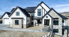 a large white house with black roofing and stone walls on the side of it