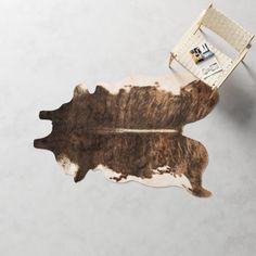 a cow hide rug on the floor in front of a chair and table with a ruler