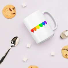 a coffee mug sitting on top of a table next to cookies and spoons