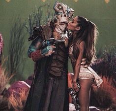 a man and woman dressed up as zombies kissing in front of a backdrop with plants