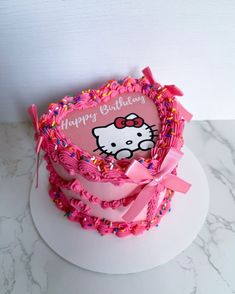 a hello kitty birthday cake with pink icing and sprinkles