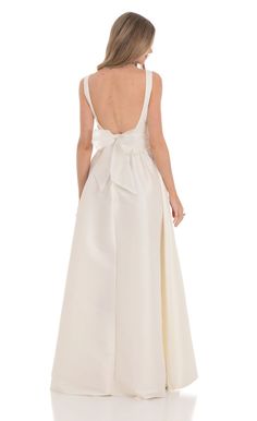 the back of a woman wearing a white dress with a bow on it's waist