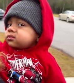 a little boy wearing a red hoodie and looking up