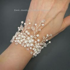 a woman's hand wearing a white bracelet with pearls and crystal beads on it