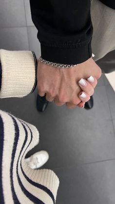 two people holding hands while standing next to each other on a tile floor with white and black stripes