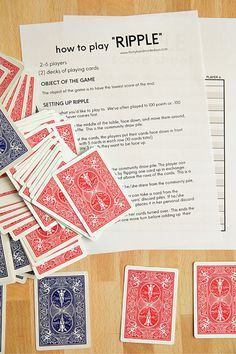 a pile of playing cards sitting on top of a wooden table next to papers and envelopes