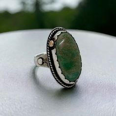 Embrace the harmonious blend of sterling silver and brass with our stunning handmade turquoise ring. Featuring a striking oval turquoise stone measuring 1 1/2 inches in length, this ring is a true statement piece. The intricate mixed metal design around the bezel adds a touch of elegance and sophistication to the piece. Meticulously crafted with care and attention to detail, this ring is a timeless addition to any jewelry collection. With its ring size of 9 3/4, it promises a comfortable and personalized fit for every wearer. Experience the fusion of beauty and craftsmanship with this exquisite handmade ring. Spiritual Benefits: Turquoise holds deep spiritual significance, known for its ability to promote inner harmony, healing, and communication. It is believed to offer protection from ne Bohemian Oval Chrysocolla Ring, Artisan Oval Ring With Patina, Spiritual Oval Turquoise Ring With Natural Stones, Bohemian Oval Turquoise Ring For Anniversary, Green Oval Turquoise Artisan Ring, Artisan Oval Green Emerald Ring, Artisan Oval Emerald Ring, Unique Oval Turquoise Ring With Patina, Green Oval Turquoise Bohemian Ring