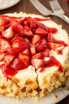 a cake with strawberries on top is sitting on a plate next to a fork