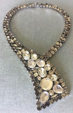 "You are looking at a truly spectacular and exquisite VINTAGE ALEXIS KIRK BOLD GEOMETRIC PENDANT FOCAL CENTERPIECE SILVER-TONE METAL STATEMENT CHOKER COLLAR BIB NECKLACE completely covered in FACETED CLEAR AND GREY DIAMANTÉ CRYSTAL RHINESTONES, in an ART DECO DESIGN WITH AN AVANT-GARDE INSPIRATION, SIGNED, Circa 1980's. IN IMMACULATE, NEVER WORN VINTAGE CONDITION, A STUNNING AND UNIQUE PIECE, SHOWCASING ALEXIS KIRK's AESTHETIC AT ITS BEST, THIS PIECE IS FULL OF SPARKLE AND WILL FIT AROUND YOUR N Antique Crystal Necklace For Formal Occasions, Vintage Stone Necklace For Wedding, Elegant Necklaces With Sparkling Stones For Vintage Events, Antique Rhinestone Necklaces For Formal Occasions, Vintage Stone Necklaces For Formal Occasions, Vintage Formal Necklaces With Stones, Vintage Crystal Embellished Jewelry For Formal Occasions, Formal Bridal Necklace With Rhinestones, Silver Crystal Bib Necklaces Costume Jewelry