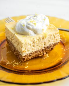 a piece of cheesecake with whipped cream on top is sitting on a yellow plate