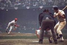 a baseball player swinging a bat at a ball in front of the catcher and umpire