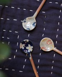 three spoons are sitting on top of a blue tablecloth with white and pink flowers