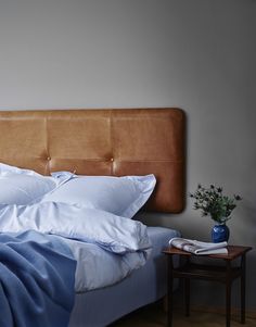 a bed with blue sheets and pillows on top of it next to a night stand