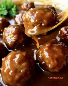 a spoon full of meatballs and gravy on a plate