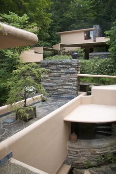 an outdoor patio area with stone walls and steps leading up to a building in the woods