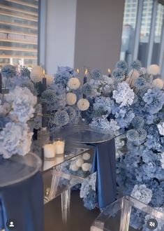 blue and white flowers are on display in front of candles