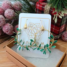 Elevate your festive style this holiday season with these exquisite handmade Christmas earrings. The gold hoop earrings are crafted with love and care, resembling the timeless beauty of a Christmas wreath. Adorned with small, delicate green resin leaves, they capture the spirit of the season in an elegant and intricate design. Whether you're treating yourself or gifting them to someone special, these earrings are a symbol of the warmth and joy that the holiday season brings.  Each earring is handmade by weaving delicate wire leaves onto brass hoops and then filling them with tinted resin. No two are alike. Specifications The hoops are 1 1/4 inch in diameter ornate fishhook style ear wires in nickel free brass total length about 2 inches Wire Leaves, Christmas Wreath Earrings, Green Christmas Wreath, Earrings Gold Hoops, Christmas Bling, Jewelry Gift Ideas, Jewelry Delicate, Earrings Green, Lightweight Earrings