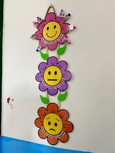 three flowers with faces hanging on a wall