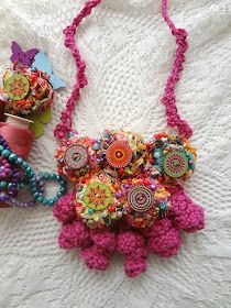 two colorful necklaces are laying on a white surface next to spools of thread