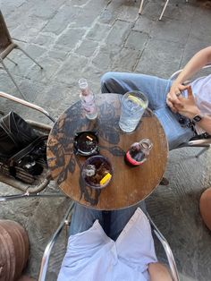 a person sitting at a table with food and drinks in front of them on the ground