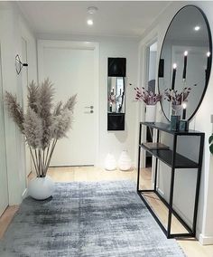 a room with a rug, mirror and vase on the floor in front of it