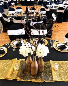 a table set up with black and gold sequins, white flowers and wine bottles