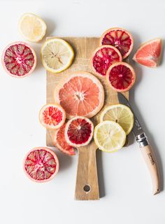 grapefruit, lemon and orange slices cut up on a cutting board with a knife