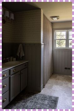 a bathroom with purple and white checkered wallpaper on the walls, gray cabinets and sink