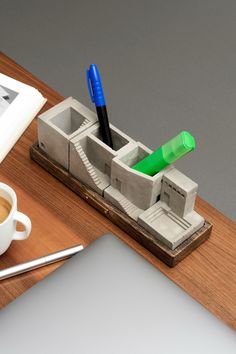 a cup of coffee sitting on top of a desk next to a pen and pencil holder