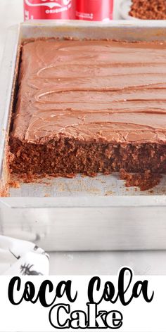 a close up of a cake in a pan with chocolate frosting and coca - cola cans behind it