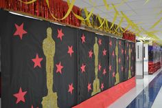 the hallway is decorated with red and gold streamers, stars, and an oscar statue