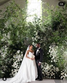 a bride and groom standing in front of a floral backdrop at their wedding ceremony,