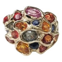 14 karat multicolored sapphire cluster ring, containing 25 round sapphires (orange, yellow, blue, green and lavender) of very fine gem quality weighing 6.43cts. This ring is a size 7 but we will size to fit for free. Luxury Elegant Cluster Gemstones, Luxury Multi-stone Classic Sapphire Ring, Luxury Multicolor Round Gemstones, Luxury Multi-stone Gold-toned Gemstones, Luxury 22k Gold Multicolor Jewelry, Luxury Multicolor Jewels Gemstones, Multicolor Sapphire Ring In Fine Jewelry Style, Multicolor Sapphire Multi-stone Ring, Multicolor Multi-stone Sapphire Ring