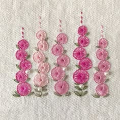 pink flowers and pearls are arranged on a white fabric background, with green stems in the center