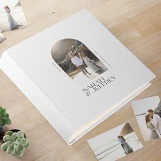 an open photo book on a wooden table with photos and succulents next to it