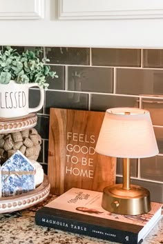 there is a lamp, book and other items on the counter in this kitchen with tile backsplash