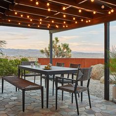 an outdoor dining area with lights strung over the table and chairs, along with potted plants