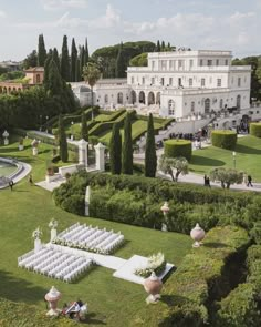 an aerial view of a wedding ceremony in front of a large white building with gardens and trees