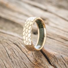 a gold wedding ring sitting on top of a piece of wood