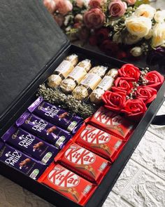 an assortment of chocolates in a box with roses on the table next to it