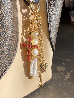 a cross is attached to a handbag with pearls and other charms on the handle