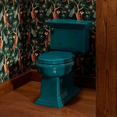 a blue toilet sitting in a bathroom next to a wall papered with peacocks