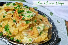 a silver plate topped with cheesy potatoes and green onions on top of a white table cloth