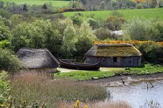 an old boat is sitting in the water near some houses with thatched roof roofs