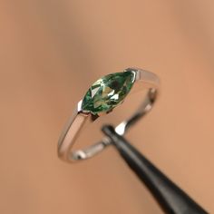 It is a green sapphire ring. The main stone is 5 mm*10 mm marquise cut.weight about 1.34 carats. The basic metal is sterling silver and plated with rhodium/14k white gold/14k rose gold/14k yellow gold You can also go to my shop Home for more elegant rings: https://www.etsy.com/shop/godjewelry?ref=hdr_shop_menu Customization is always welcome and please feel free to contact with me if you have any design ideas! Modern Marquise Cut Promise Ring Jewelry, Modern Jewelry With Prong Setting And Marquise Cut, Modern Jewelry With Marquise Cut And Prong Setting, Modern Marquise Cut Jewelry With Prong Setting, Silver Marquise Emerald Ring, Elegant Silver Marquise Emerald Ring, White Gold Jewelry With Marquise Cut Tension Setting, Modern Marquise Cut Jewelry With Tension Setting, Modern Silver Marquise Jewelry