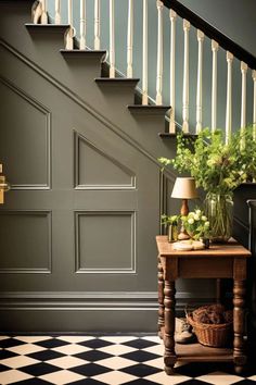 a table with flowers on it next to a stair case in a room that has black and white checkered flooring