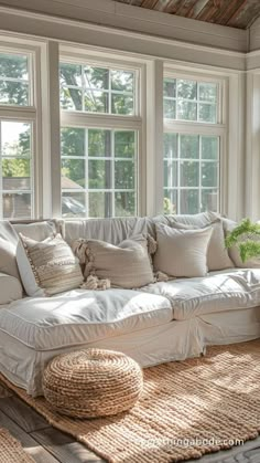 a living room filled with lots of white furniture and pillows on top of a rug