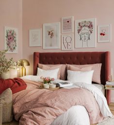 a bedroom with pink walls and pictures on the wall above the bed, along with a red velvet headboard